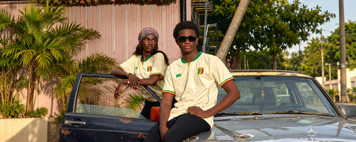 Deux jeunes en maillot Mali 2026 devant une Mercedes à Bamako